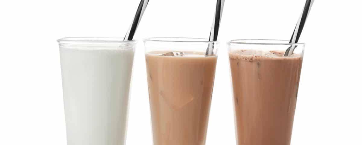 Glasses with different protein shakes and powders in spoons on white background