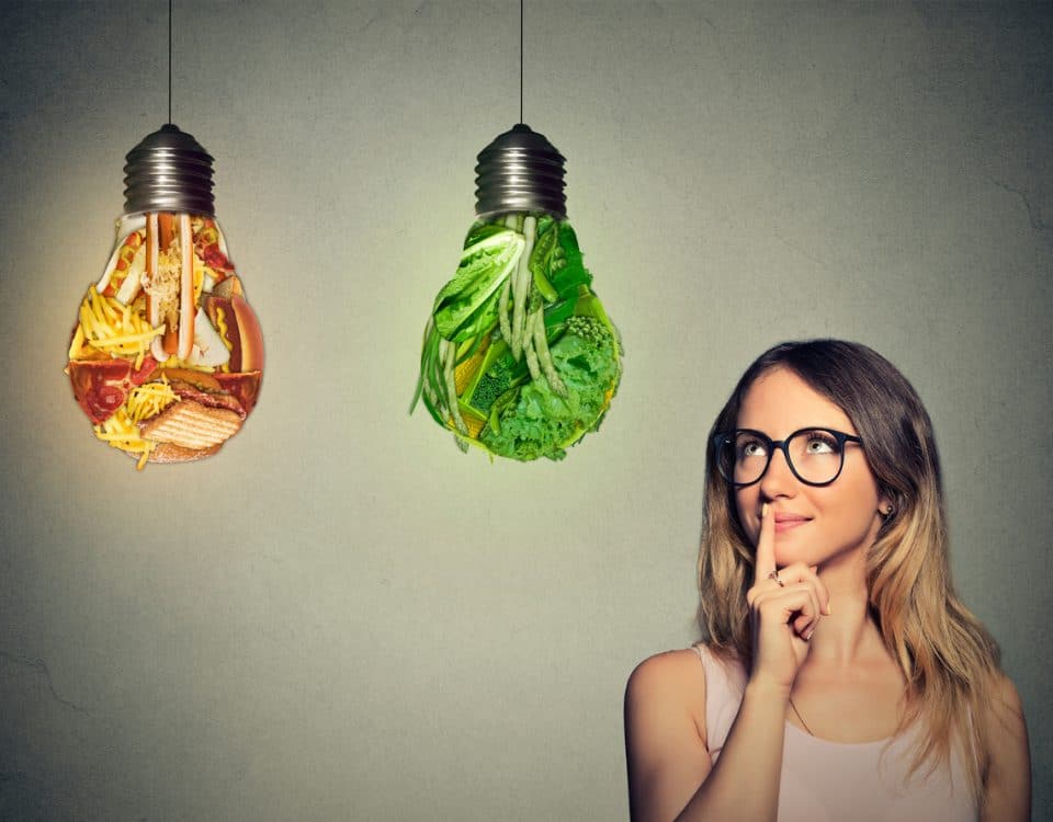 Portrait beautiful woman in glasses thinking looking up at junk food and green vegetables shaped as light bulb isolated on gray background. Diet choice right nutrition healthy lifestyle concept