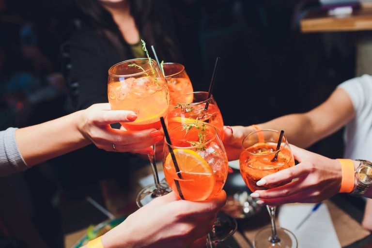 women raising a glasses of Spritz at the dinner table.